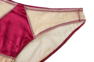 Detailed close-up of seamless red satin fabric with beige mesh lace and premium stitching