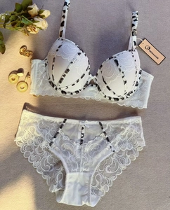 Dettaglio di un set di lingerie in pizzo bianco con bordi con stampa mucca bianca e nera