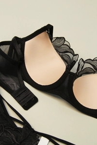 Detail of black lace bra with floral embroidery and breathable mesh side panels
