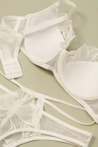 Detailed close-up of white floral lace embroidery on sheer mesh lingerie set