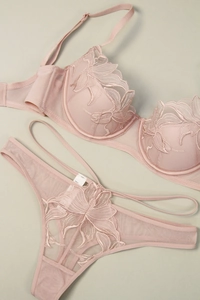 Macro detail of pale pink lace embroidery and delicate mesh fabric on the bra set