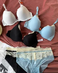 Detailed view of three lace bra and panty sets in white, black and light blue colors