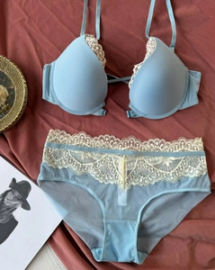 Detailed close-up of light blue lace lingerie set with white eyelash trim on red background