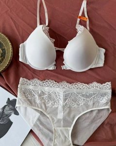 Detail of white lace lingerie set with front-closure bra and sheer panties on red fabric