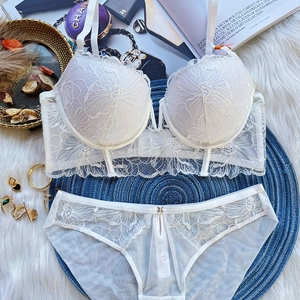 Flat lay of white floral lace lingerie set with mesh panties on a plush decor background