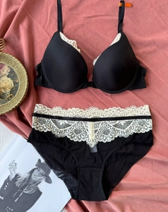 Detailed flat lay of black and cream lace lingerie set with floral embroidery and silk fabric