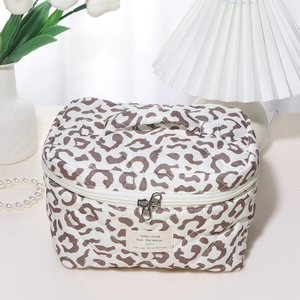 Quilted leopard print toiletry bag with zipper and handle in a cozy home setting