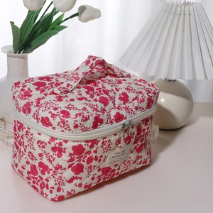 Close-up of floral quilted cosmetic bag with dual metal zippers and top handle