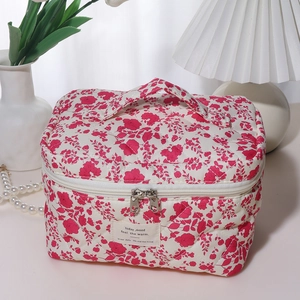 Detailed macro view of floral quilted cotton makeup bag with dual zippers and woven label