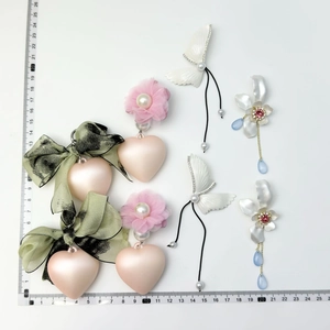 Detailed view of pearl bow heart charms and floral tassels with a measurement scale ruler