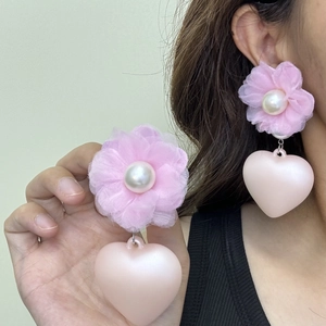 Pink fabric floral heart earrings with faux pearl detail shown on ear for fashion
