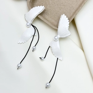 Detailed close-up of feather-shaped earrings with pearls and long black tassels
