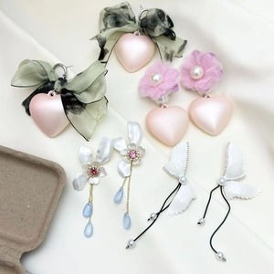 Detailed view of various heart and bow pearl earrings on a soft white satin background