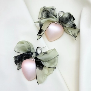 Close-up of green chiffon bow earrings with leopard print and pink heart charms