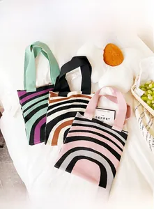 Detailed view of three knitted striped tote bags in green, brown, and pink color options