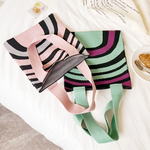 Knitted tote bags with wide stripe patterns in pink, grey and green displayed on white fabric