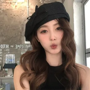 Detail of black houndstooth wool beret with side bow decoration on a female model