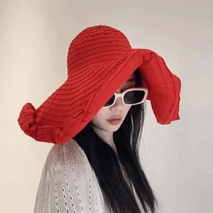 Close-up of red wide-brim woven sun hat with wavy edges and horizontal texture