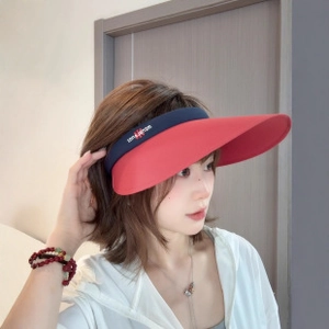 Detail of red wide brim sun visor with dark blue elastic headband featuring sun embroidery