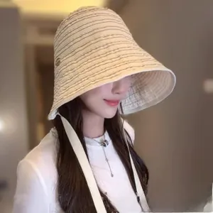 Detail of cream woven sun hat with black fine patterns and elegant side tie strap