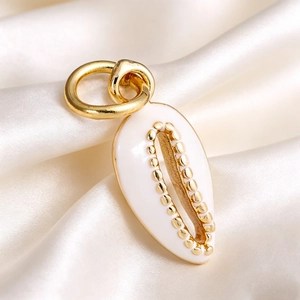 Macro detail of white shell-shaped pendant with golden bead trim on silk background