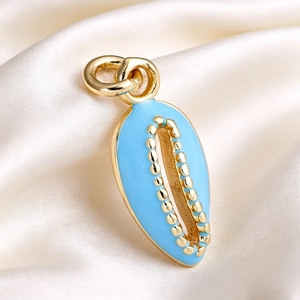 Macro shot of blue enamel shell pendant with gold-plated bead trim on silk fabric