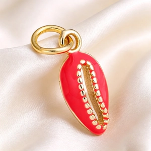 Macro shot of shell pendant with red enamel and gold finish on elegant silk background