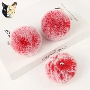 Close-up of pink pompom poodle keychain with leather details on a white book