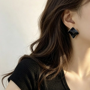 Elegant geometric square black enamel stud earrings with gold plating on model