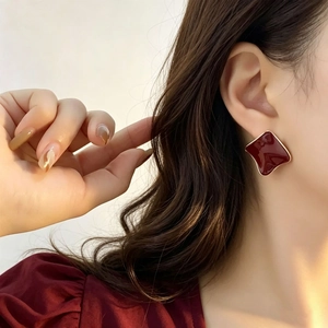 Retro geometric square enamel stud earrings in gold and deep red on a model's ear