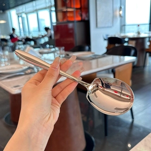 Close-up of polished stainless steel serving spoon held in a restaurant setting
