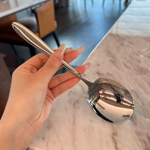 Macro shot of mirror-polished stainless steel spoon head with smooth ergonomic handle
