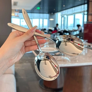 Macro shot of mirror-polished stainless steel serving spoons on a marble table