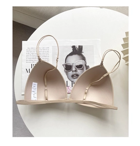Detail of a seamless wireless triangle bra in beige with adjustable straps on a white table