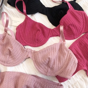 Detail of French lace bras in black, rose, and pink with wave knit texture
