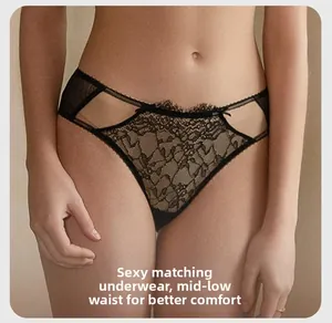 Detail der passenden schwarzen Spitzenslip in Schwarz mit Blumenmuster und Schleifen
