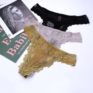 Detailed view of three lace thong panties in black, lilac and ochre yellow with dot mesh