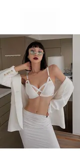 Dettaglio reggiseno bianco con lacci e cinturini incrociati sotto un blazer