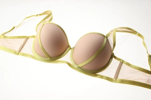 Dettaglio reggiseno push-up bicolore con bordi verdi e ali in rete beige trasparente