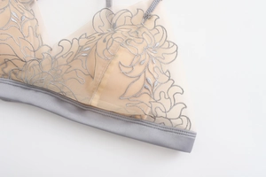 Dettaglio di reggiseno in pizzo francese con ricamo floreale grigio su tessuto a rete fine