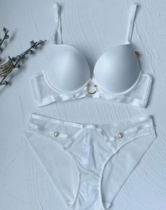 Flat lay of a white seamless lingerie set with sheer mesh and gold ring accents