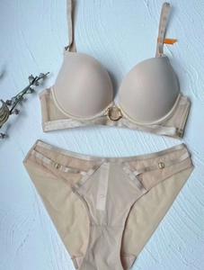Detail view of seamless push-up bra and mesh panty set with gold ring accents in nude color
