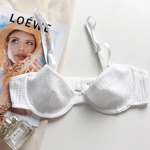 Detailed close-up of white lace bra texture with adjustable strap and interior sizing label