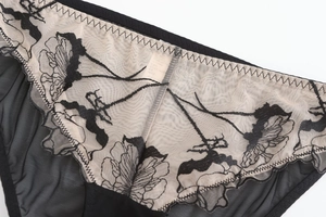 Détail de la maille noire semi-transparente et de la broderie florale en dentelle fine