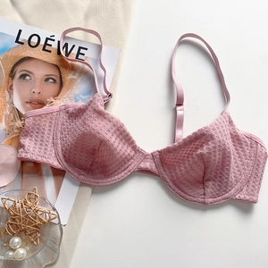 Detailed macro view of pink lace bra with waffle mesh texture and adjustable metallic strap