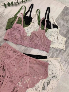 Flat lay of lace bra and panty sets in pink, white, black, and dark green colors