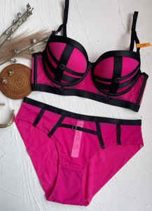 Detail of fuchsia lace lingerie set with black contrast straps and mesh texture