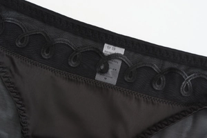 Gros plan détaillé sur culotte en tulle noir avec broderie florale et finitions satin
