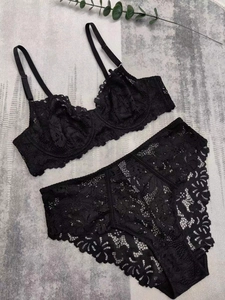 Flat lay of black floral lace lingerie set with bra and high-waist panties on marble