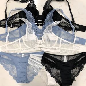 Flat lay of French lace lingerie sets in black, light blue, and white with adjustable straps